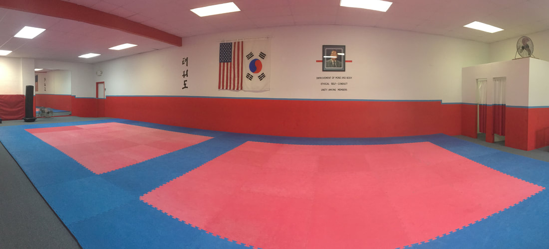 A long and narrow classroom with red and blue mats
