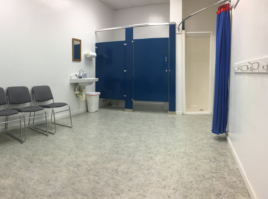A clean and bright changing room with white walls and a blue bathroom stall